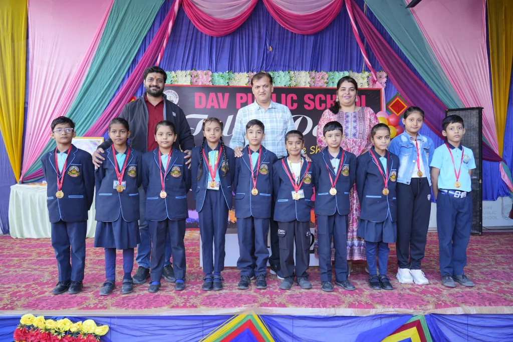 Award-winning students of D.A.V. Public School Suratgarh posing with medals and teachers on Annual Function stage – Best School in Suratgarh for holistic development